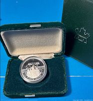 Coin in open velvet case showing reverse design and capsule
