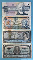 Fronts of four $5 notes stacked: 1985, 1954, 1979, 1937