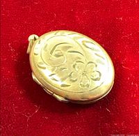 Front view showing engraved floral and scroll design on oval locket
