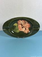 Front view of Moorcroft oval ashtray showing hibiscus design and rests