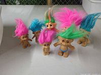 Front view of seven troll dolls showing hair colors and sizes