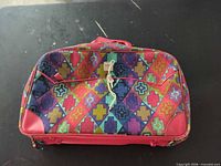 Front view of red multicolor travel bag with lock and keys attached