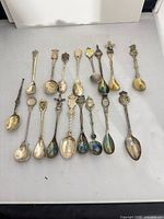 All 17 souvenir teaspoons laid out together