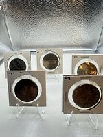 Group view of five Canadian dollar coins in individual flips on stands