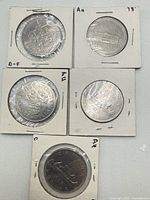 Overview of five Canadian dollar coins in paper holders