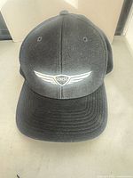 Front view of black Genesis baseball cap showing embroidered wing logo