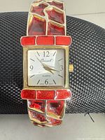 Front view of gold-tone watch with red enamel bracelet