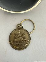 Front view of brass keychain showing embossed Four Queens Hotel & Casino logo and anniversary text
