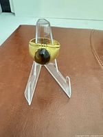 Front view of gold-filled ring with dark brown cabochon stone on display stand