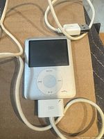 Front view of silver iPod nano with click wheel and attached 30-pin cable