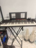 Keyboard on stand with music rest and cables visible