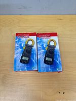 Two boxed DT3266L digital clamp meters on table