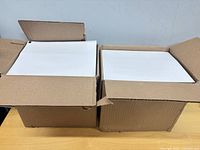 Two open boxes showing stacks of white cardstock inside