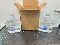Two Purell sanitizer refill cartridges standing beside opened shipping box
