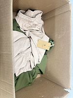 Top view showing beige elastic-waist bottoms and green garment with tag