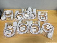 Nine individually bagged white shower head sets on tabletop