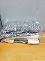 Stack of four sealed pillows showing two grey hexagon and two white patterns