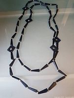 Full view of black geometric bead necklace laid flat