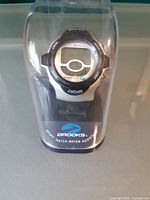 Watch on retail plastic stand inside clear cover showing BROOKS SPORT branding and WR30M marking