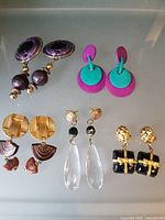 Group shot of all five earring pairs displayed on glass shelf