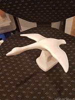 Side view of white ceramic swan sculpture showing wings and base