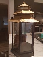 Full view of lantern on countertop showing wood frame, glass panels, metal pagoda roof