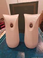 Front view of two white Air Wick automatic dispensers standing side by side