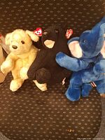 Group shot of beige dog, black bear, blue elephant Beanie Babies with tags