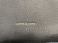 Close-up of pebbled black vegan leather with gold Love & Lore logo