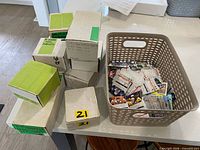 Overview of several white card storage boxes stacked beside a beige plastic basket filled with loose cards