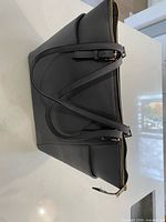 Side profile showing structured shape, pebbled texture, straps and gold zip