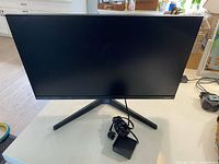 Front view of monitor on Y-shaped stand, power adapter coiled on base