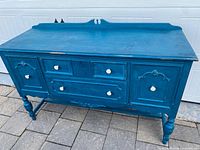 Front view of peacock blue sideboard showing drawers, doors, knobs, turned legs