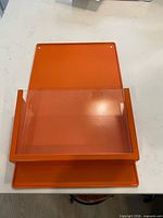 Front view showing orange metal panel and clear acrylic pocket