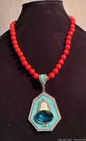 Necklace on bust showing red beads and pendant front