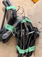 Bundle of black plastic hangers taped together showing variety and metal hooks