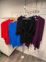 Four sweaters on hangers: red, blue, black, wine