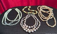 All four necklaces laid out on black surface