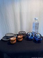 Group showing all items: blue glass oil candles, lamp oil bottle, metal plates, wood tealight holders, scrollwork holder