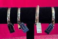 Four Monet gold-tone bracelets on display bar with tags visible