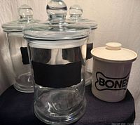 Front view of three glass canisters and one ceramic bones canister