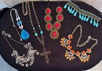 Group shot of all eight necklaces arranged on black surface