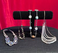 Group shot of all four necklaces on display stand