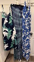 Three dresses hanging: floral maxi, tie-dye strapless maxi, leaf-print tank