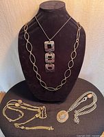 Group shot of all four necklaces displayed on bust and table