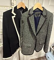 Both blazers hanging: black with white trim and J.Crew tweed with satin trim