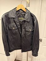 front view of black leather Danier jean-style jacket on hanger