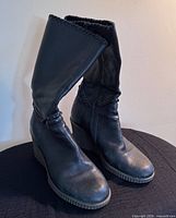 Front three-quarter view of both boots showing overall design, leather texture and wedge heels