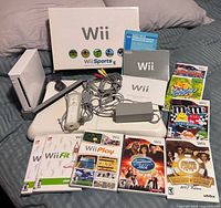Overview of Wii console, balance board, remote, sensor bar, cables, manuals, and game cases