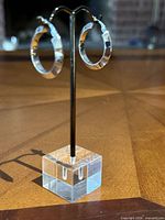 Pair of white gold hoop earrings on stand